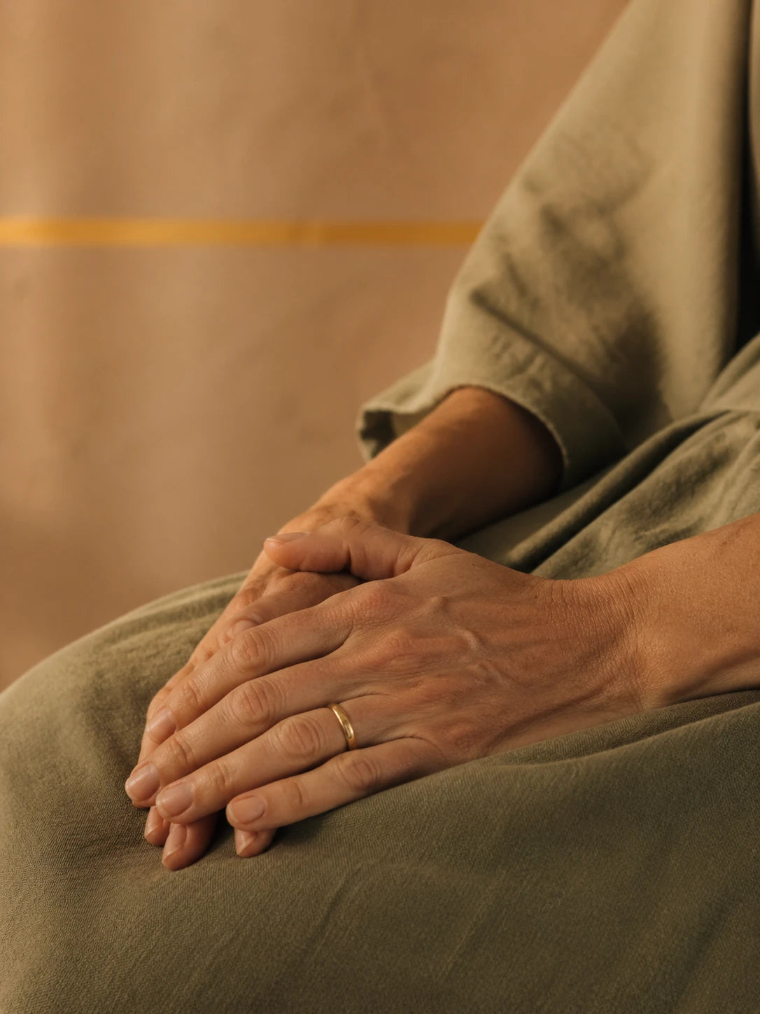 Hands resting on a sage olive linen robe