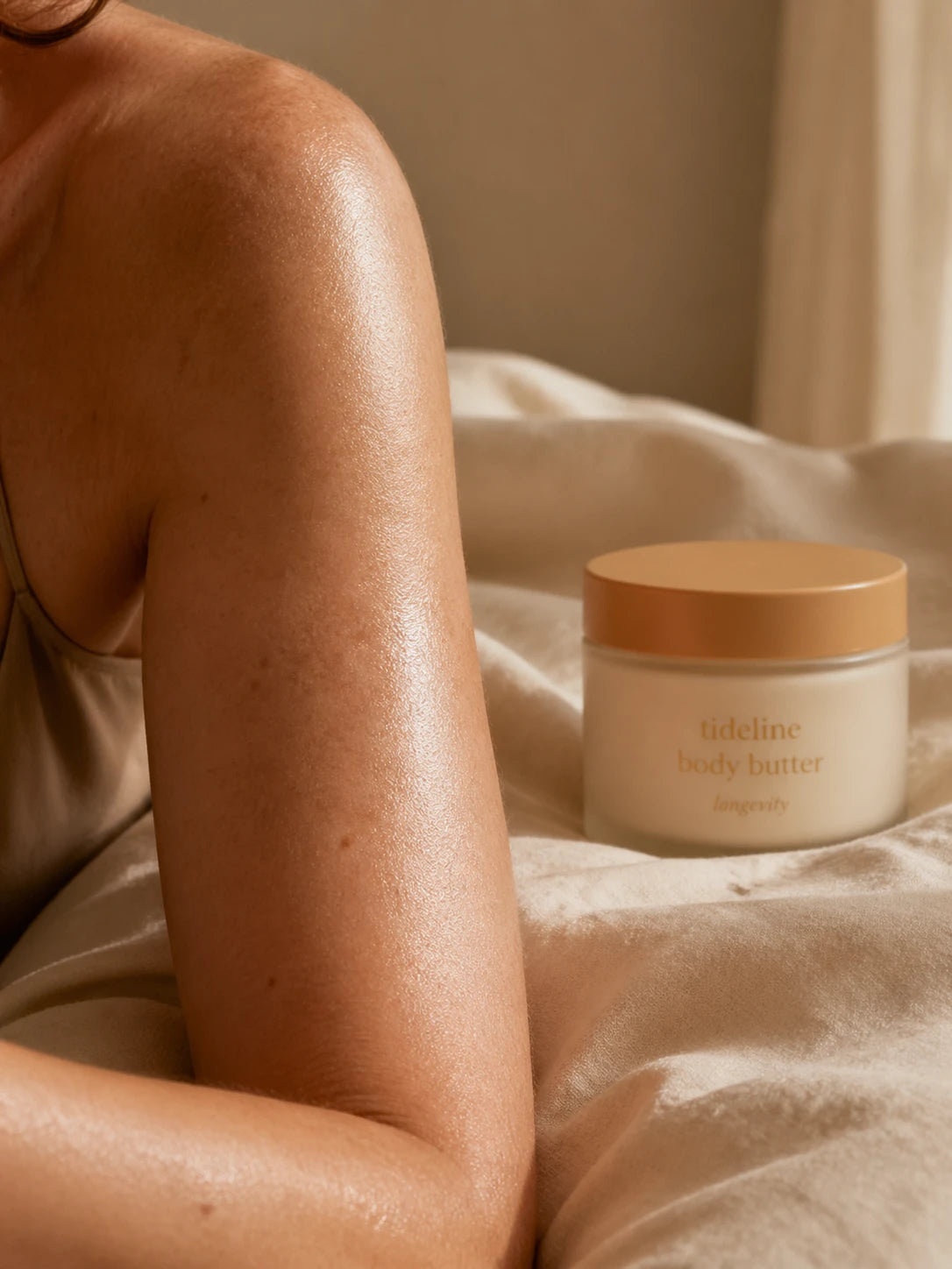Daily butter glistening on a freshly-applied shoulder, jar in soft focus
