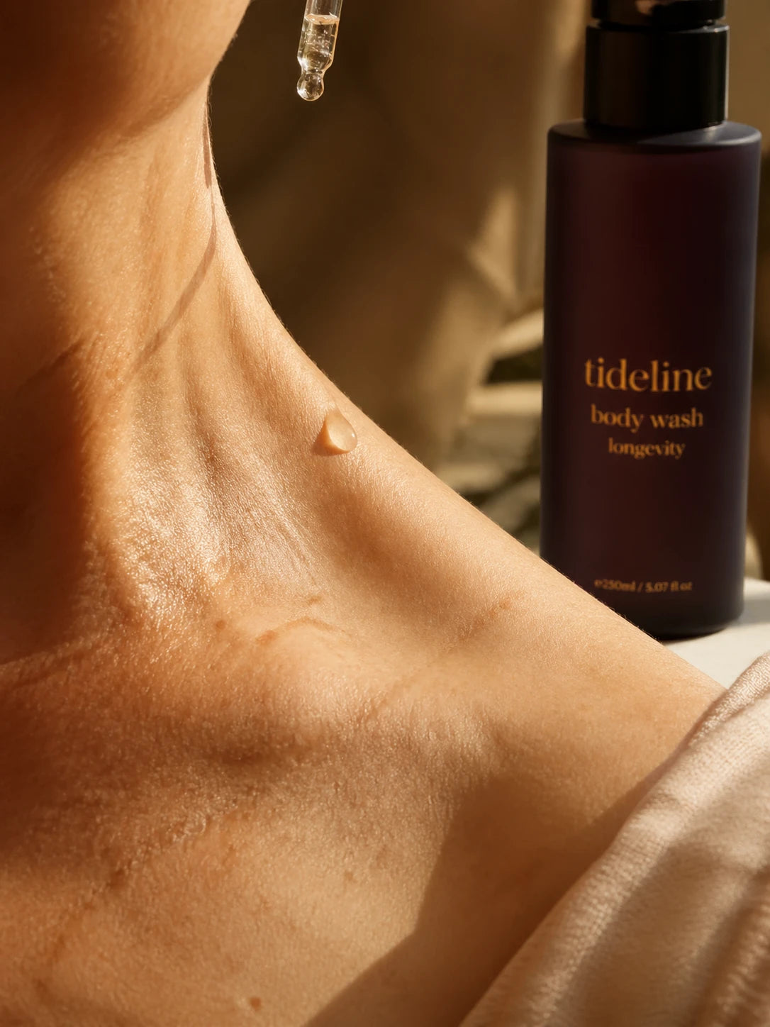 Daily Wash being poured onto bare collarbone skin in tungsten light