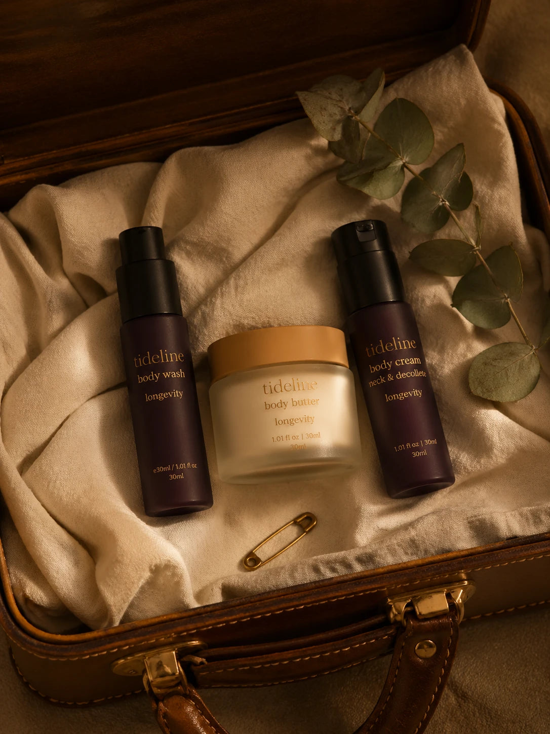 The travel trio laid on bone-cream linen inside an open vintage tan leather suitcase
